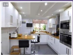 a kitchen with white cabinets and a counter top at Cheerful 4- Bedroom Detached House with Portable in Addington