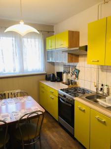a kitchen with yellow cabinets and a table and a stove at Apartament Gosia in Rogowo