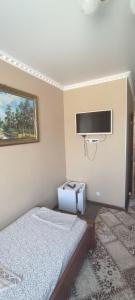 1 dormitorio con 1 cama y TV de pantalla plana en Готель Адріана, en Dunaivtsi