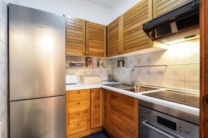 une cuisine avec des armoires en bois et un réfrigérateur en acier inoxydable dans l'établissement Duomo Luxury Apartment VI, à Milan