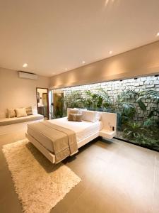 a bedroom with a bed and a large window with plants at Casa ADOBE Preá - FRENTE MAR! in Prea