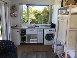 a kitchen with a sink and a washing machine at Sunset Cottage in Tauranga