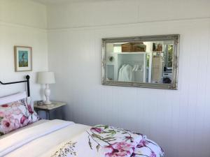 a bedroom with a bed and a mirror on the wall at Sunset Cottage in Tauranga