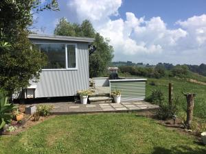 a tiny house in a garden with a patio at Sunset Cottage in Tauranga