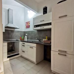 uma cozinha com armários brancos e um lavatório em Hostel Pipištrelo em Pula