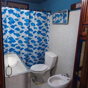 a bathroom with a toilet and a blue and white shower curtain at Hostal El Puesto in Salto