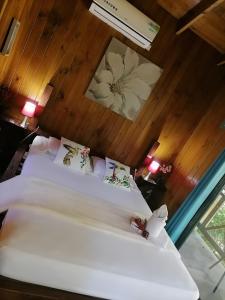 a bedroom with two white beds and a wooden wall at Casa el Colibrí in Parrita