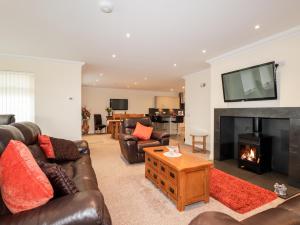 a living room with leather furniture and a fireplace at Riverside Cottage in Portree