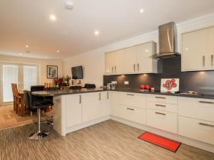 a kitchen with white cabinets and a dining room at Riverside Cottage in Portree
