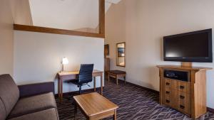 a hotel room with a couch and a flat screen tv at Best Western Plus Saddleback Inn and Conference Center in Oklahoma City