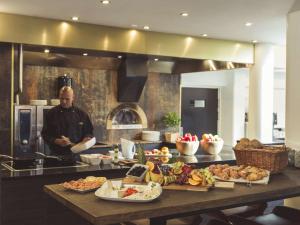 a man standing in a kitchen with a table of food at Radisson Blu Limfjord Hotel, Aalborg in Aalborg