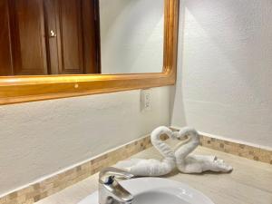 two towels shaped like swans sitting on a bathroom sink at Aurinko Bungalows in Sayulita +59 photos