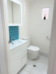 een witte badkamer met een toilet en een wastafel bij The Lake Guesthouse in Budgewoi