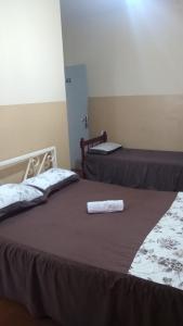 two beds in a hotel room with towels on them at Hotel Brasil in Presidente Prudente