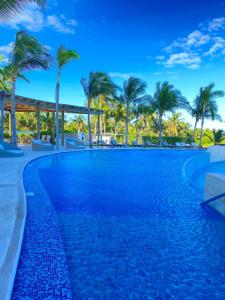 a swimming pool at a resort with palm trees at Ocean front apartment in Cancun in Cancún