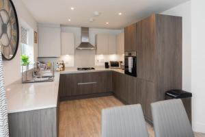 une cuisine avec des placards blancs et un comptoir dans l'établissement Greenfield's - New Modern 3 Bedroom Home - Johnstonen Close, Bracknell, à Bracknell
