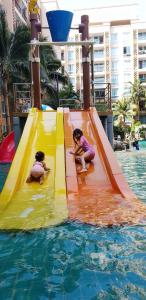 deux petites filles jouant sur un toboggan dans l'eau dans l'établissement Atlantis Condo Resort Jomtian Pattaya, à Jomtien Beach