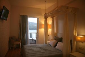 1 dormitorio con cama con dosel y balcón en Mirini Hotel en Samos