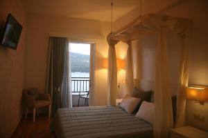 a bedroom with a canopy bed and a balcony at Mirini Hotel in Samos