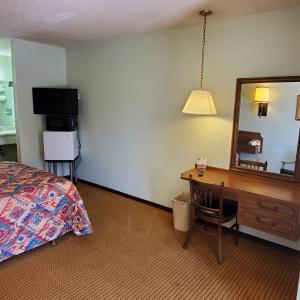 um quarto com uma cama, uma secretária e um espelho em Robin Hood Motel em Raton