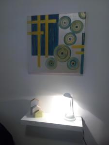 een lamp op een plank met een schilderij op de muur bij HOSPEDAJE DEL PARQUE- Zona centro de Monte Grande-15 min del Aeropuerto de EZE!! ESTACIONAMIENTO GRATIS! in Monte Grande