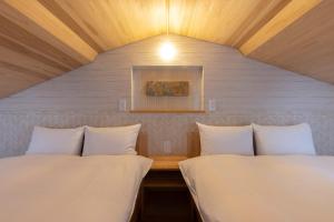 two beds in a room with a ceiling at Kyomachiya Suite Rikyu in Kyoto