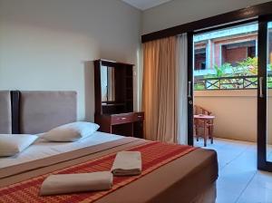 a bedroom with a large bed and a balcony at Sapta Petala Hotel in Kuta