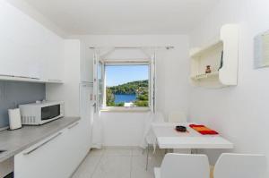 a white kitchen with a table and a microwave at Apartment Lucija - with Pool in Rogač