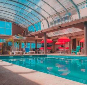 a swimming pool with tables and chairs and umbrellas at Gran Hotel Fontainebleau in San Clemente del Tuyú
