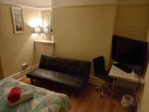 a bedroom with a couch and a desk and a television at 52 Cambrian St in Aberystwyth