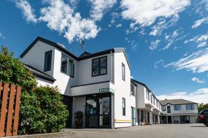 un edificio bianco con un cielo sullo sfondo di Riccarton Mall Motel a Christchurch