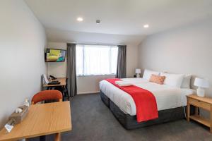 a hotel room with a bed and a desk and a table at Riccarton Mall Motel in Christchurch