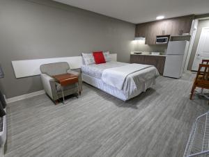 a bedroom with a bed and a chair and a kitchen at Riverside Motel & Suites in Medicine Hat