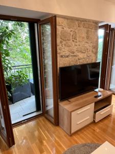 ein Wohnzimmer mit einem Flachbild-TV und Glasschiebetüren in der Unterkunft Apartment Old Town Ivo in Makarska
