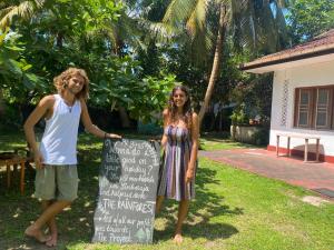 a man and a woman standing next to a sign at Siri medura surf yoga meditation guesthouse and hostel in Weligama