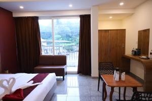 a hotel room with a bed and a chair and a table at Hillfort Inn in Sultan Bathery