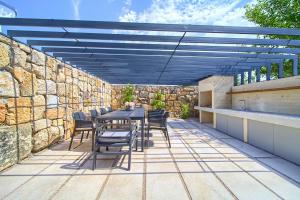 a patio with a table and chairs and a stone wall at Luxury Jerini Estate in Krk