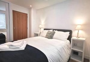 a bedroom with a large bed with white sheets and pillows at Apartment in the heart of East Wittering Village in Chichester