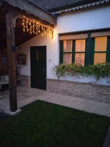 a house with a porch with a green door and lights at Veranda Vendégház in Verőce