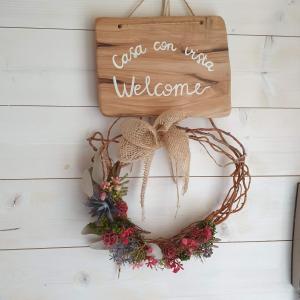 a wreath on a white table with a welcome sign at Casa con vista in Corniolo