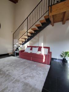 een rode bank in een woonkamer met een trap bij La corte dell'orologio in Endine Gaiano