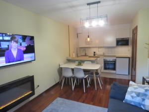 een woonkamer met een tafel en een tv aan de muur bij Ático Dúplex reformado con vistas a la montaña in Canfranc-Estación