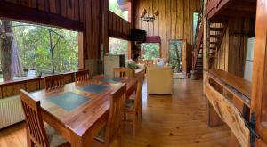 Cabañas Natural Park Lodge Pucon في بوكون: غرفة طعام مع طاولة طويلة وأرضيات خشبية
