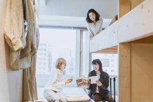 two women sitting on a loft bed looking at a book at The Stay Sapporo in Sapporo