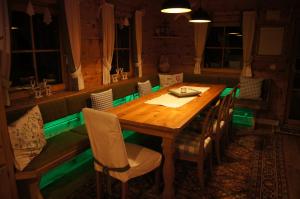 una sala da pranzo con tavolo in legno e luci verdi di Chalet Steiermark a Pusterwald