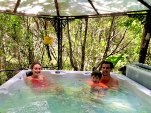 Ein Mann, eine Frau und ein Kind in einer Badewanne. in der Unterkunft Cabañas Natural Park Lodge Pucón in Pucón + 127 Fotos