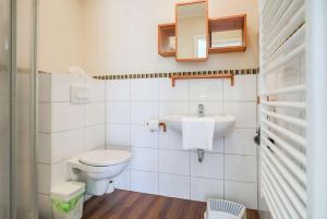 a white bathroom with a toilet and a sink at Buedlfarm-SuedOst in Sahrensdorf