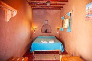 Un pequeño dormitorio con una cama azul en una habitación en La Maison de l'Homme Bleu, en Aït Boukha