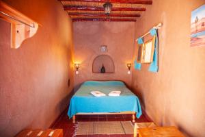 a small bedroom with a blue bed in a room at La Maison de l'Homme Bleu in Tighmert