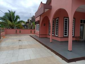 a pink building with a courtyard and palm trees at BJ villa homestay in Kuala Terengganu